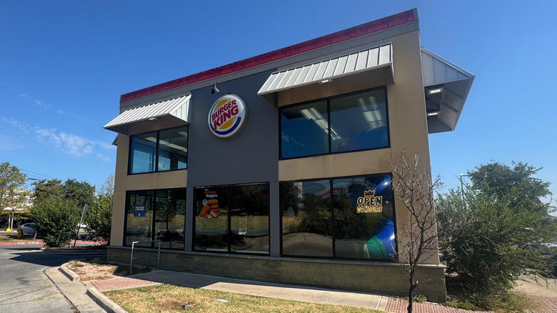 Exterior of a gray Burger King with a blue sky in the background.