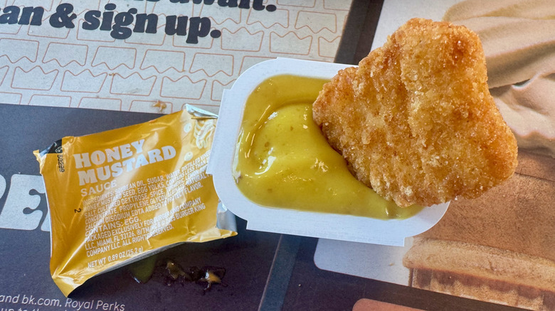 A nugget dipped in a yellow honey mustard sauce.