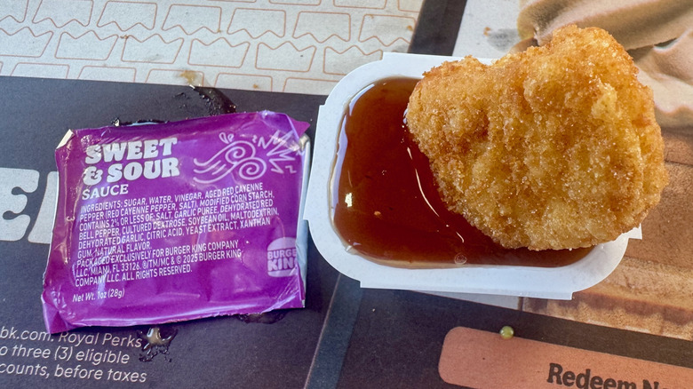 A nugget dipped in a red, syrupy sweet and sour sauce.