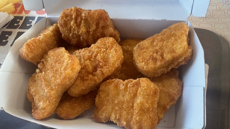 Crispy brown chicken nuggets in an open cardboard container.