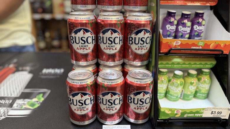 Cans of Busch Light Apple in rows in display on liquor store counter