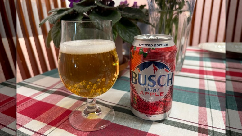a poured glass of Busch Light Apple next to a can of the beer on table