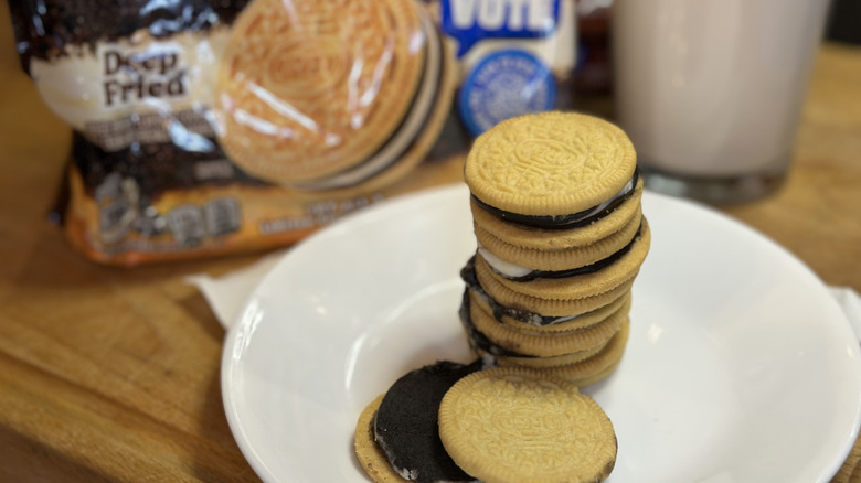 Oreo Deep Fried in a stack on a white plate with package and glass of milk in the background