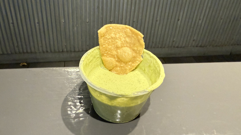 a chip rests in a cup of Chipotle's Cilantro Lime Sauce