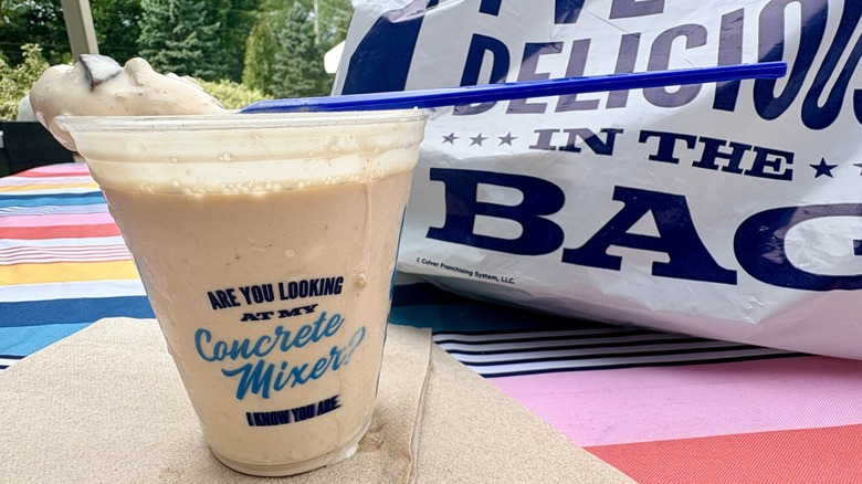 A closeup of Culver's new Pumpkin S'mores Concrete Mixer for fall in takeout cup on table next to Culver's takeout bag