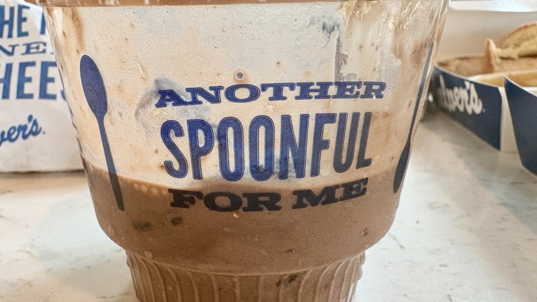 A half empty takeout cup of Culver's Peanut Butter Fudge Brownie frozen custard