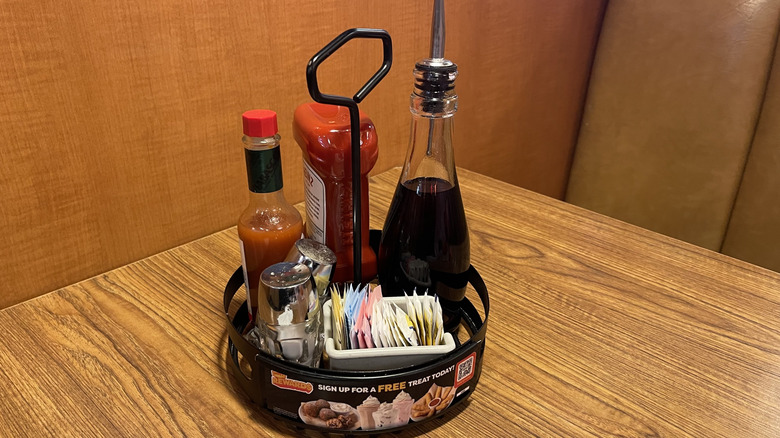 A booth at Denny's with a tray of condiments