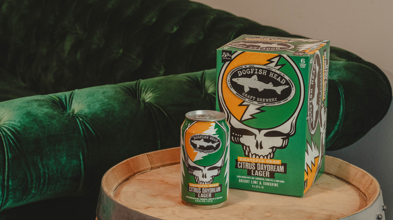 Can of Dogfish Head Grateful Dead Citrus Daydream Lager and box sits on barrel next to velvet sofa