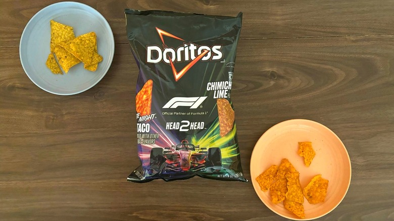 Bag of Doritos F1 Head2Head chips on table betweeen two plates with different flavors of the chips, including Late Night Loaded Taco and Chimichurri Lime