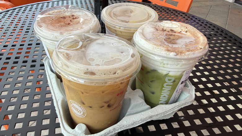 Four Dunkin' tiramisu cold beverages in a drink holder on a metal table