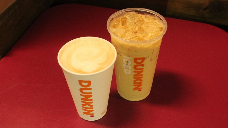 Hot and iced Dunkin' beverages on pink table
