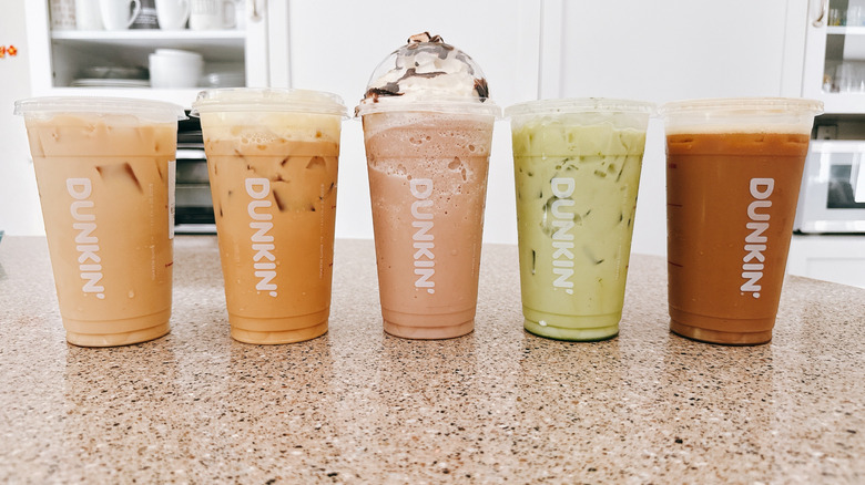 A variety of Dunkin' iced beverages in plastic cups on a granite counter
