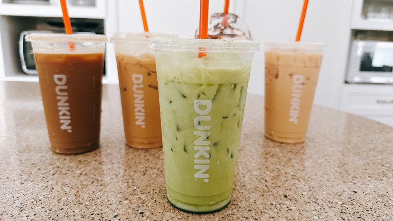 Several Dunkin' beverages in plastic cups on a granite counter