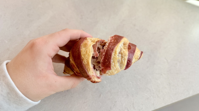 Hand holding opened raspberry croissant