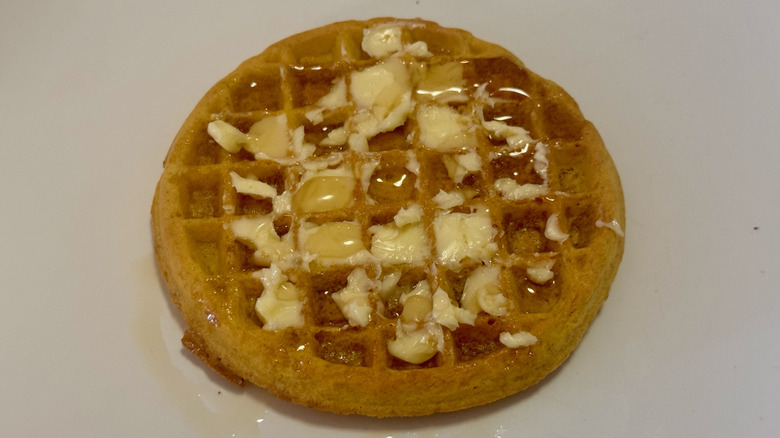 A toasted waffle with butter and maple syrup