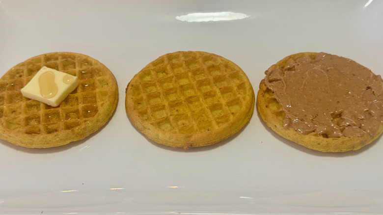 Three pancakes prepared with different toppings in a straight line on a white plate