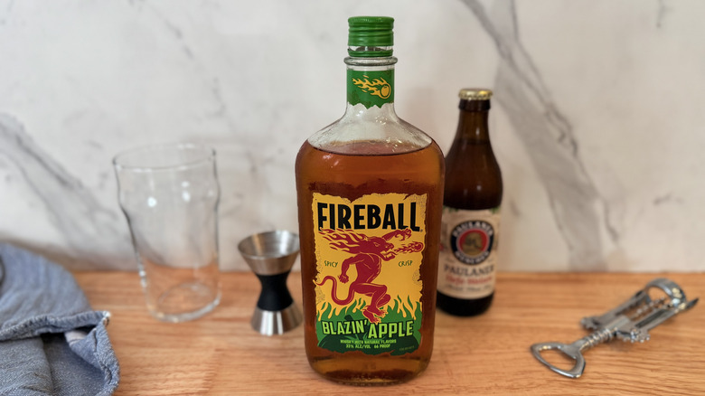 Ingredients set out for beer and whisky mix with bottle of Fireball Blazin Apple in the foreground