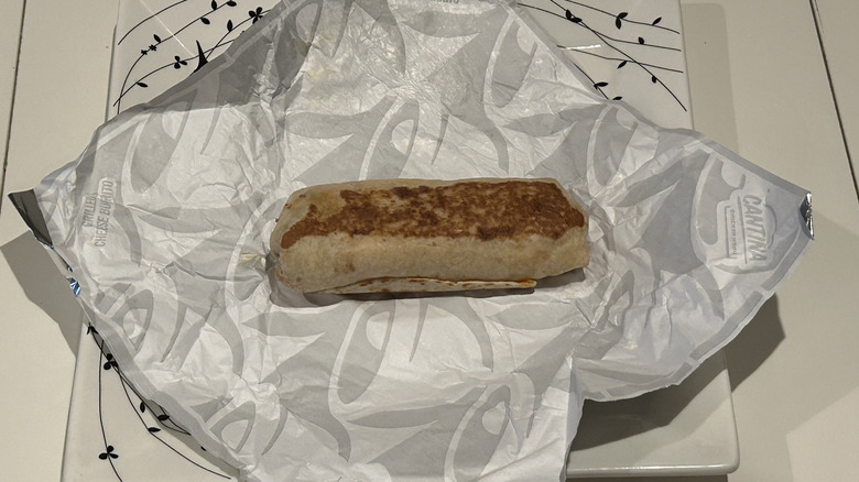 An uneaten Volcano Quesarito on a plate, next to a rose for scale