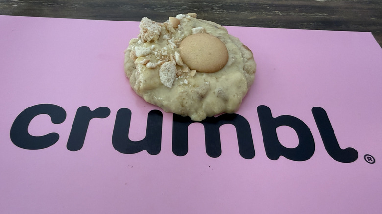 Banana Cream Pie Cookie on top of a pink box with the Crumbl logo