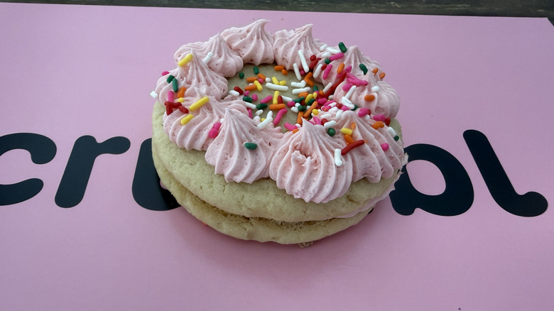 Crumbl Ice Cream Cake Sandwich Cookie on top of a pink Crumbl box