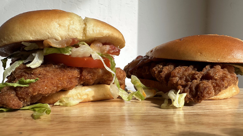 McDonald's Bacon Buffalo Ranch McCrispy deluxe sandwich next to McDonald's bacon buffalo ranch standard McCrispy on wooden table