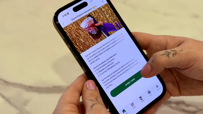 Hands holding a phone with the screen showing the order for Starbucks' Hannah Montana Popstar Refresher