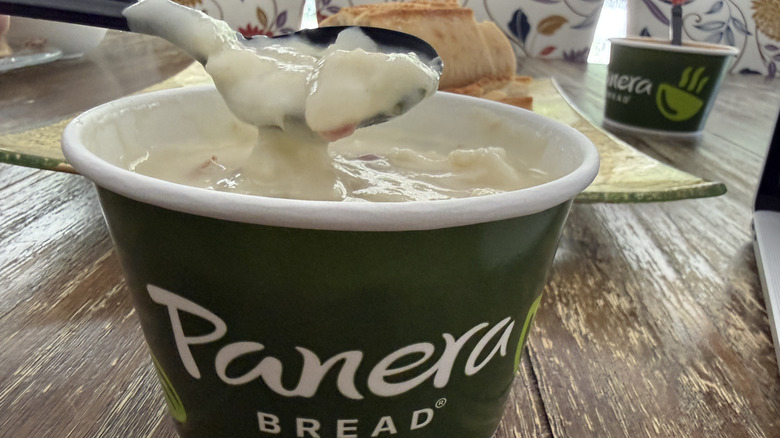 Panera Rustic Baked Potato Soup on wooden table with bread in background