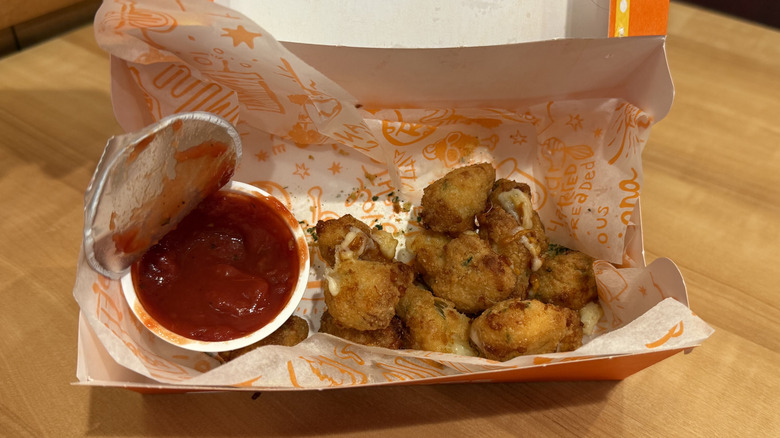 an open box of Popeyes' Cheesy Bites with Marinara Sauce