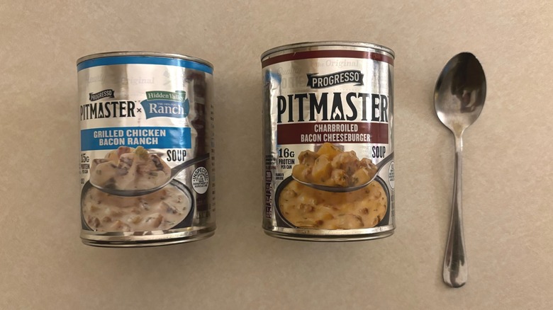 Progresso Pitmaster Grilled Chicken Bacon Ranch Soup and Progresso Pitmaster Charbroiled Bacon Cheeseburger Soup cans side by side with spoon
