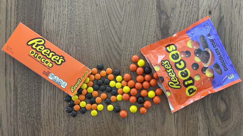 Reese's Pieces original and with chocolate cookies spilled side by side on table