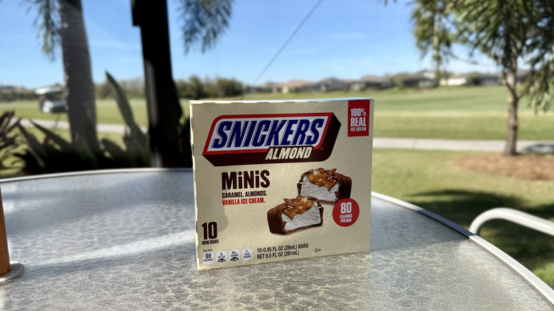 A box of Snickers Almond Ice Cream Minis on an outdoor table