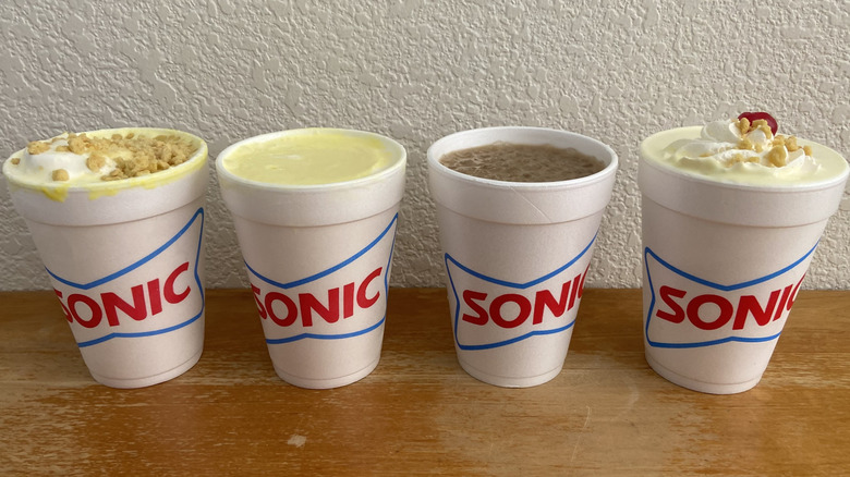 All four Sonic banana drinks with no lids in horizontal row on table