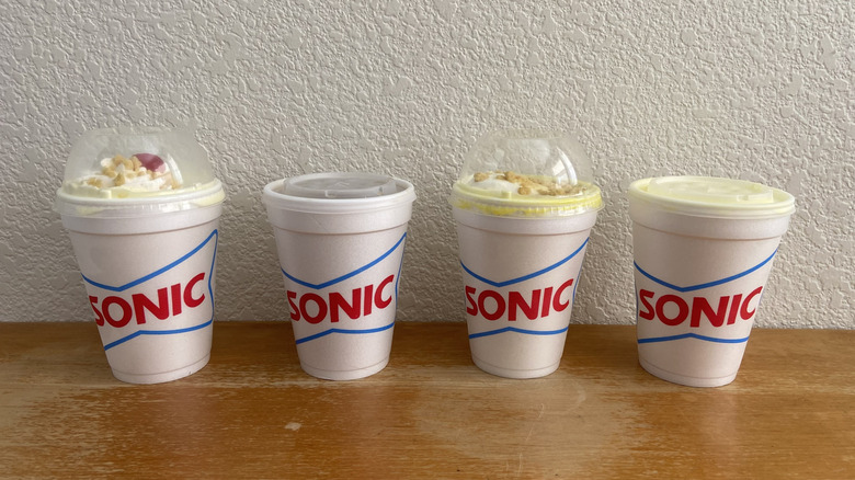 all four Sonic banana drinks in a horizontal row on a wooden table