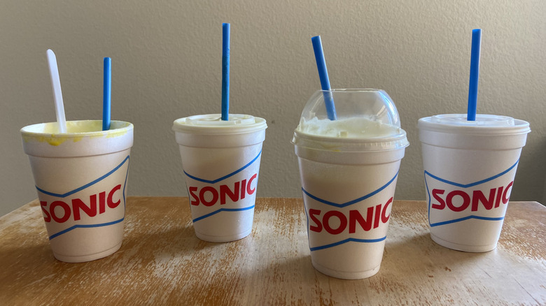 all four Sonic banana drinks, half-finished, with straws sticking out of the cups, in dramatic lighting