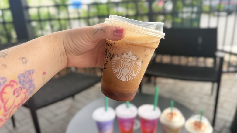 Hand holding a Iced Horchata Shaken Espresso from Starbucks in a plastic to-go cup