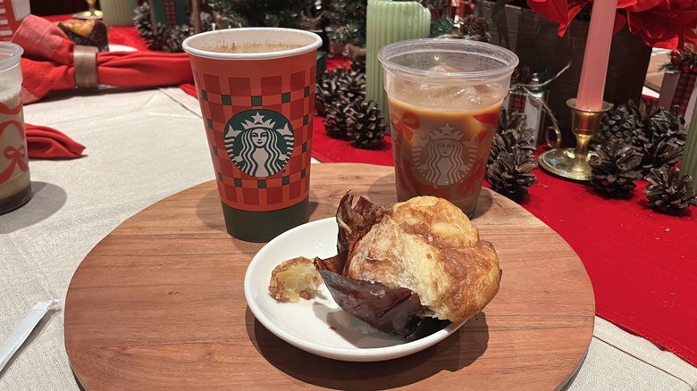 A Starbucks Eggnog Latte next to an iced coffee with eggnog cold foam and a cinnamon pull apart muffin