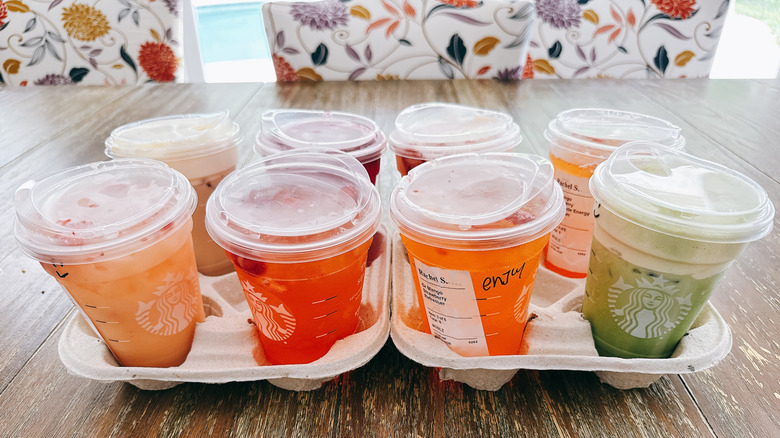 eight starbucks mango drinks in cardboard carriers on wooden table