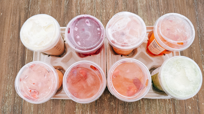 Top view of new mango infused drinks in cardboard carrier on wooden table