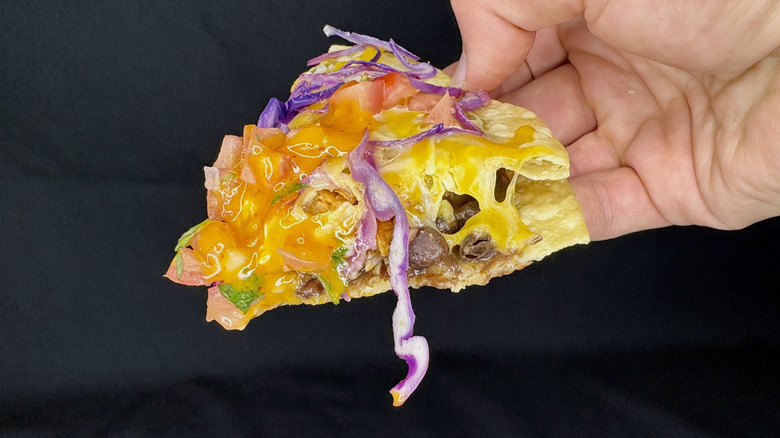 hand holding slice of taco bell pizza