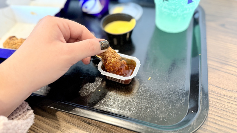Hand dipping nugget into Mike's Hot Honey Diablo Sauce