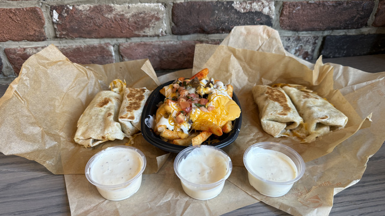 Taco Bell's Creamy Garlic Sauce in front of burritos and nacho fries