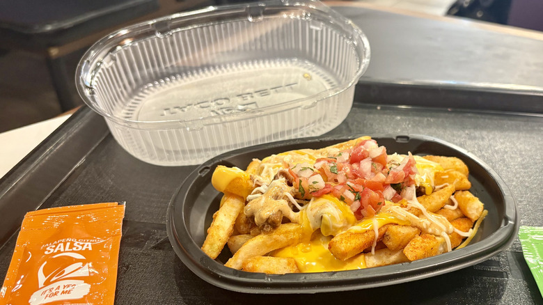 Shredded Beef Nacho Fries from Taco Bell on a tray next to some salsas and its lid