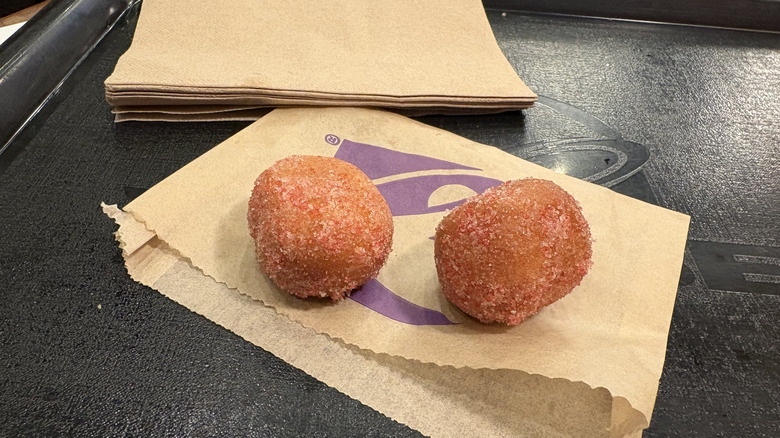 Two Strawberry Cinnabon Delights sitting on their wrapper on a tray with some napkins