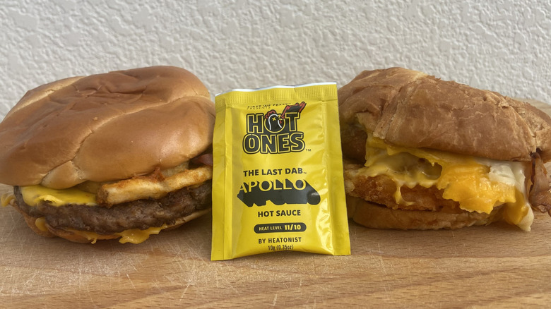 Both sandwiches on a cutting board with the Hot Ones The Last Dab: Apollo hot sauce packet between them