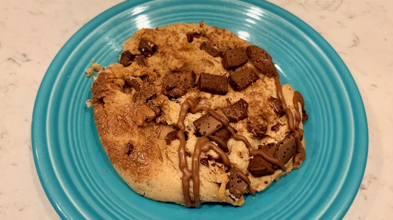 A closeup of King Krumb drizzled chocolate chunk cookie on a blue plate