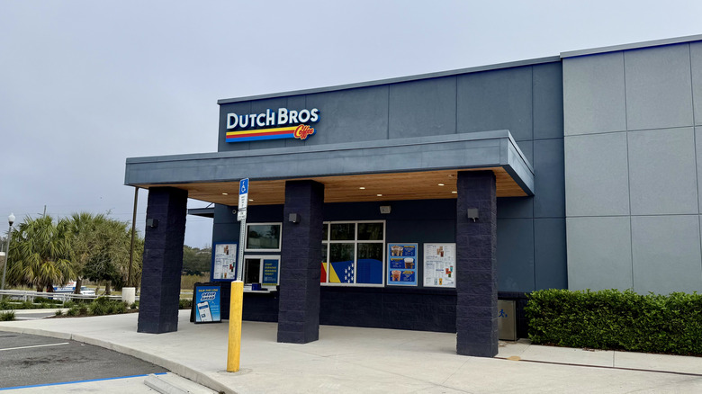 Exterior of large, modern Dutch bros location with row of bushes