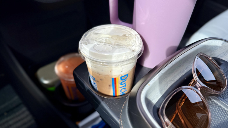 Close up of Dutch Bros iced coffee drink with soft top in a car's cupholder