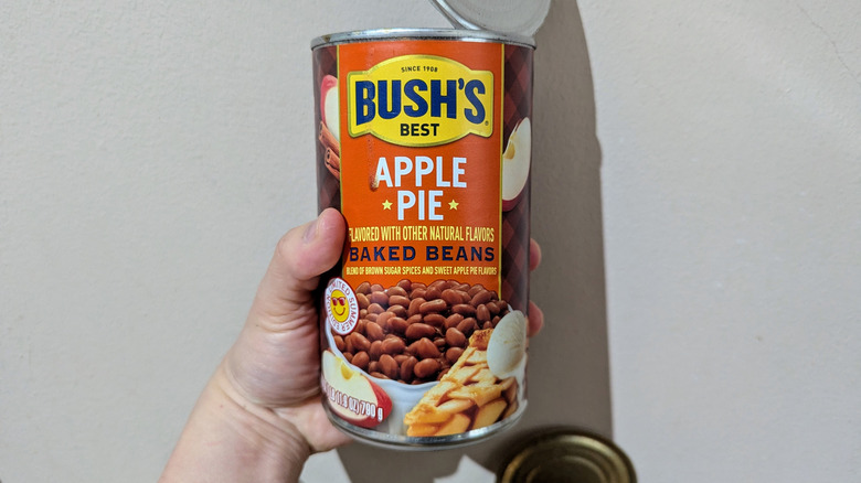 Hand holding an open can of Bush's Apple Pie-flavored baked beans