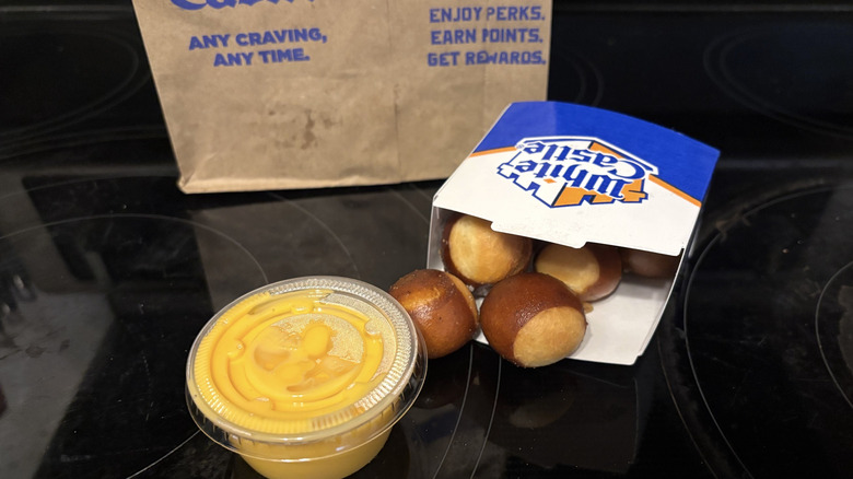 White Castle Pretzel Nibblers with cheese, boxes, and bag on black background.