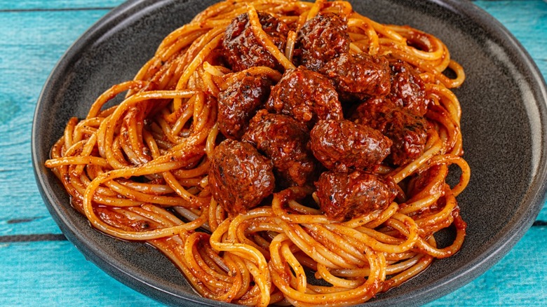 spaghetti and meatballs in black bowl